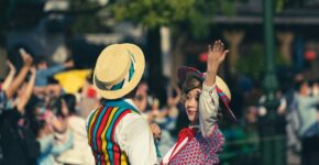 To folkedansere i fargerike drakter danser foran et publikum