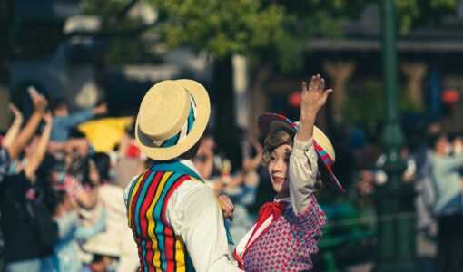 To folkedansere i fargerike drakter danser foran et publikum